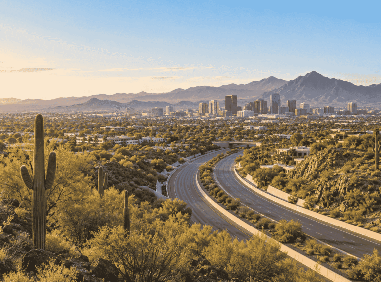 High-angle view of a highway curve heading toward the Phoenix city skyline with desert mountains near Scottsdale in Scottsdale
